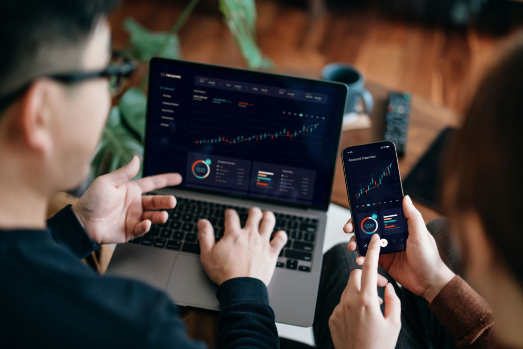Small business owners review financial or marketing performance data on a laptop and smartphone